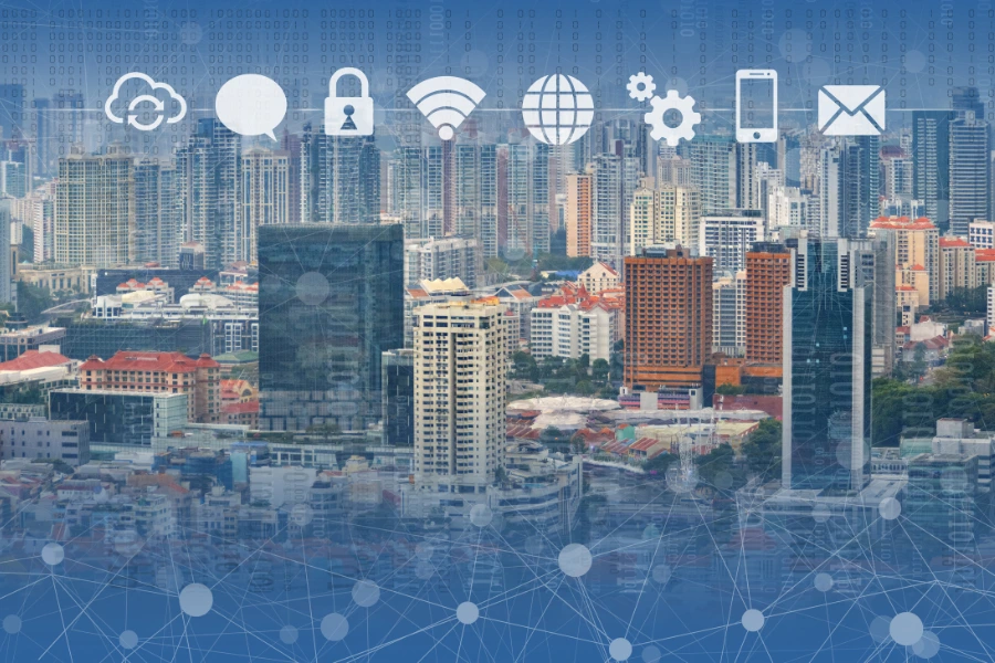 Paisagem urbana de uma cidade moderna com altos edifícios e infraestrutura robusta, sobreposta a ícones digitais representando conectividade, incluindo nuvem, comunicação, cadeado (segurança), Wi-Fi, globo (internet), engrenagens (processos automatizados), smartphone e e-mail. Em primeiro plano, uma rede interligada em estilo futurista simboliza a Internet das Coisas (IoT), destacando a integração da tecnologia no ambiente urbano e conectividade inteligente.
Tecnologias disruptivas que vão mudar o mundo até 2030.